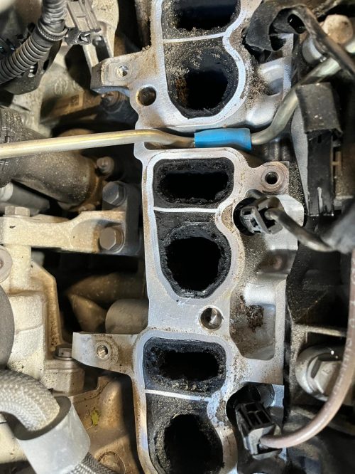 Extreme Ölkohle-Ablagerungen und Verkokung in den geöffneten Einlasskanälen eines Automotors bei ATT-Baudisch.